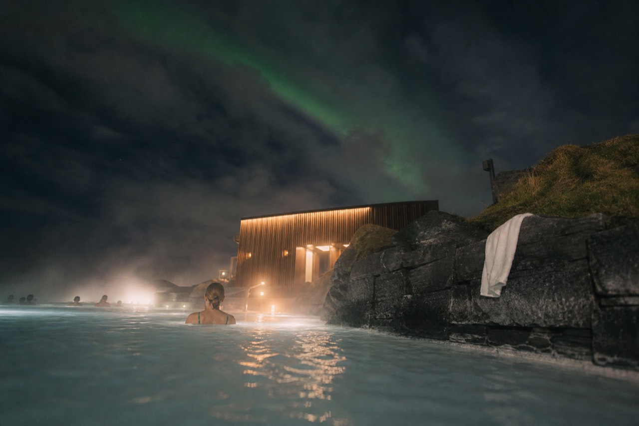 Steam rising from a geothermal lagoon at the ocean's edge under a dark winter sky