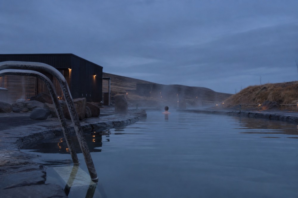 A steaming geothermal pool at dusk with steam rising over still water