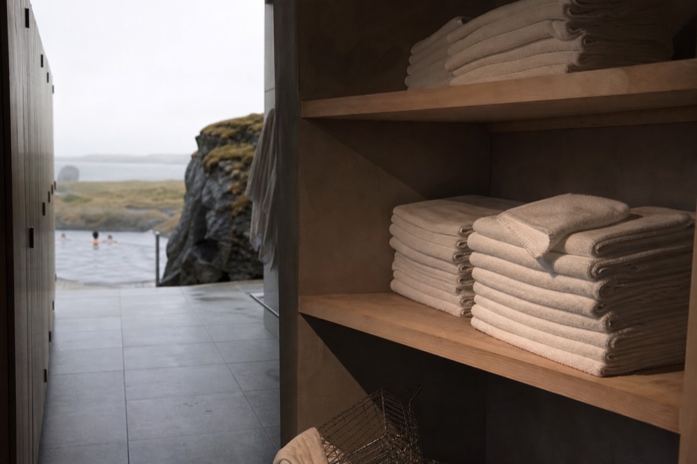 Neat stacks of white towels on a wooden shelf beside a spa changing area