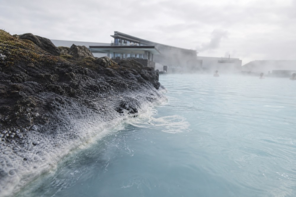 Milky blue geothermal water lapping against dark volcanic rock