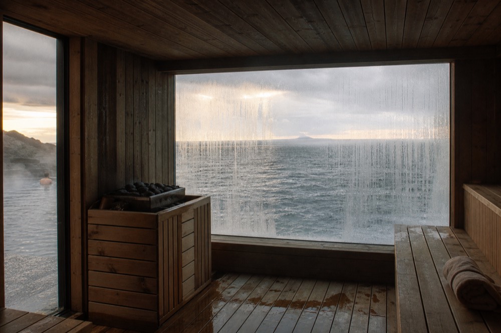 A wooden sauna with a large window facing the open ocean