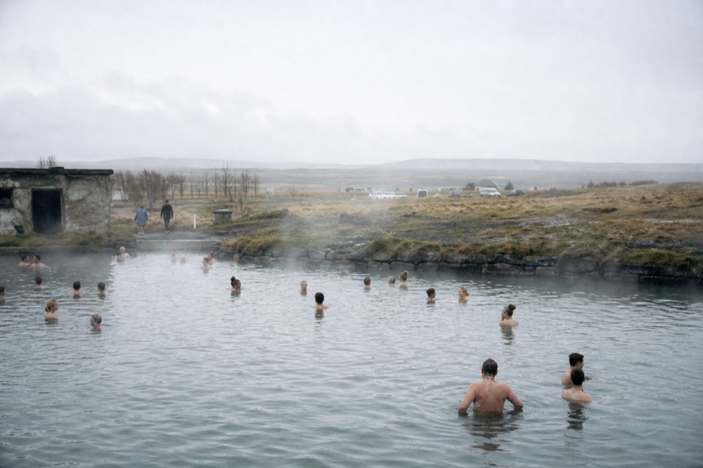 Still water of a warm outdoor pool with steam drifting across a low horizon