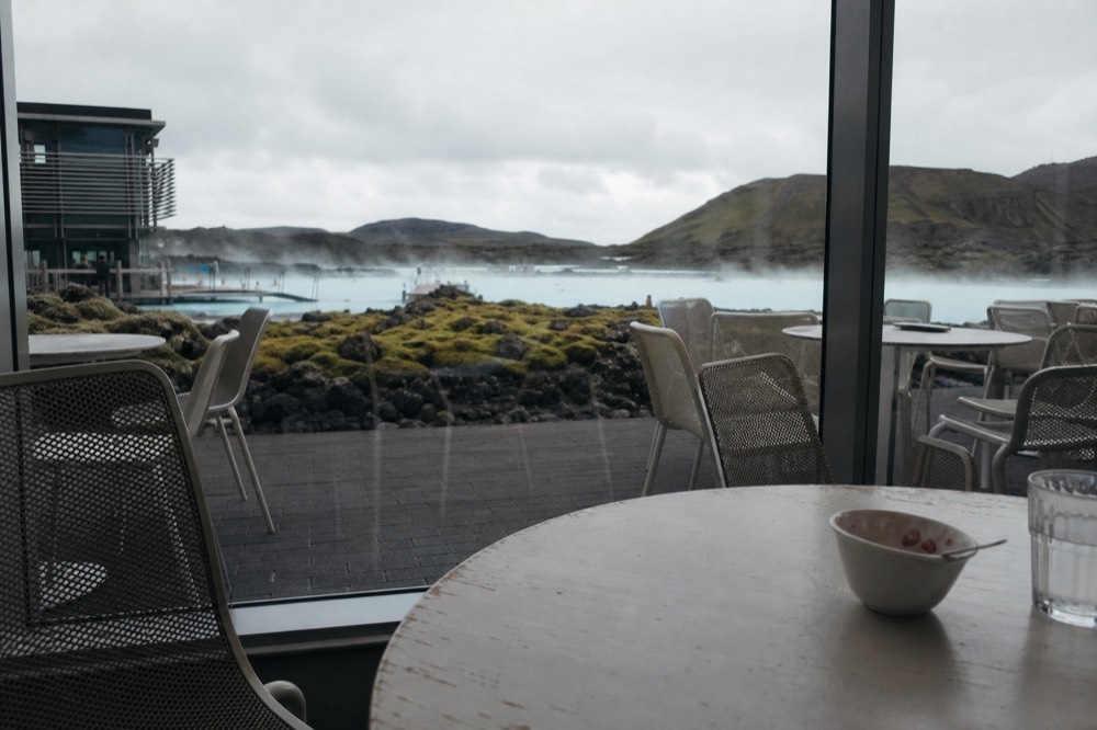 Cafe seating area with a view over a steaming geothermal lagoon