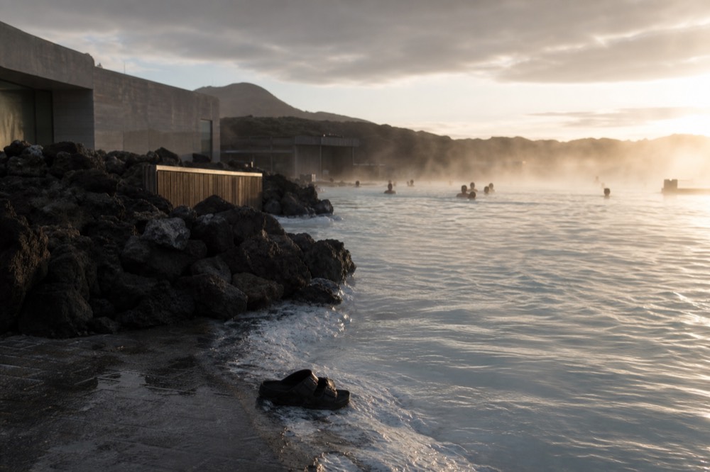 Warm evening light on steaming water with wet rocks and a calm grey sky