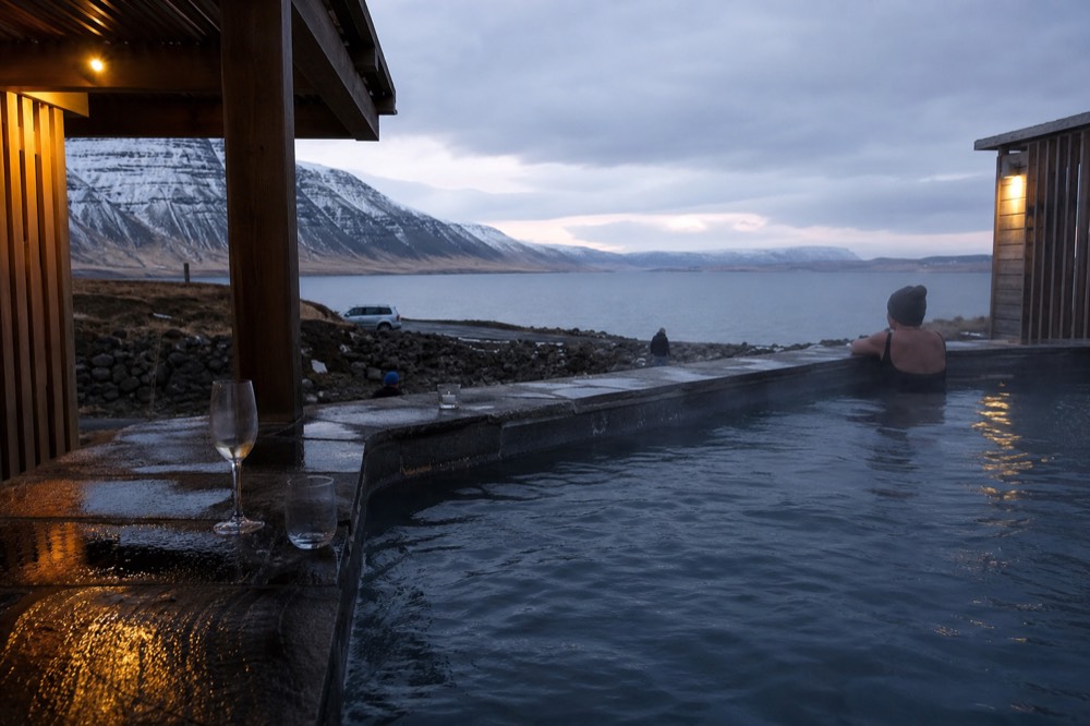 A swim-up bar counter set into a steaming geothermal pool at dusk