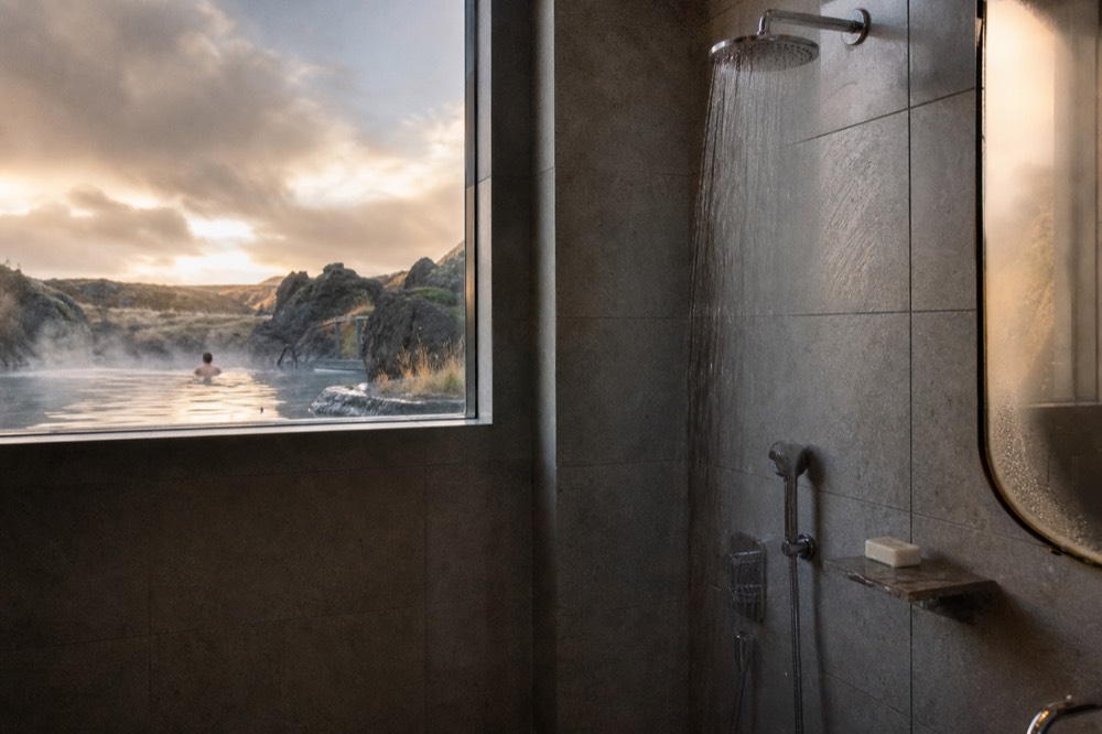 Warm water pouring from a shower head in a tiled spa washroom