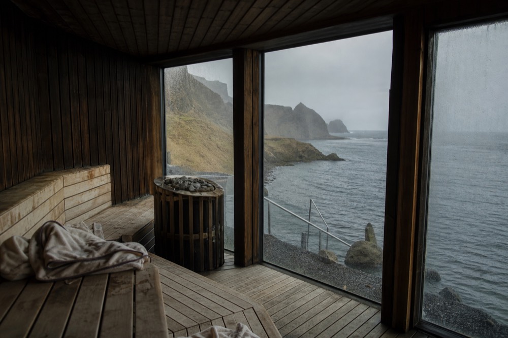 Wooden sauna with a large window looking out over dark ocean water