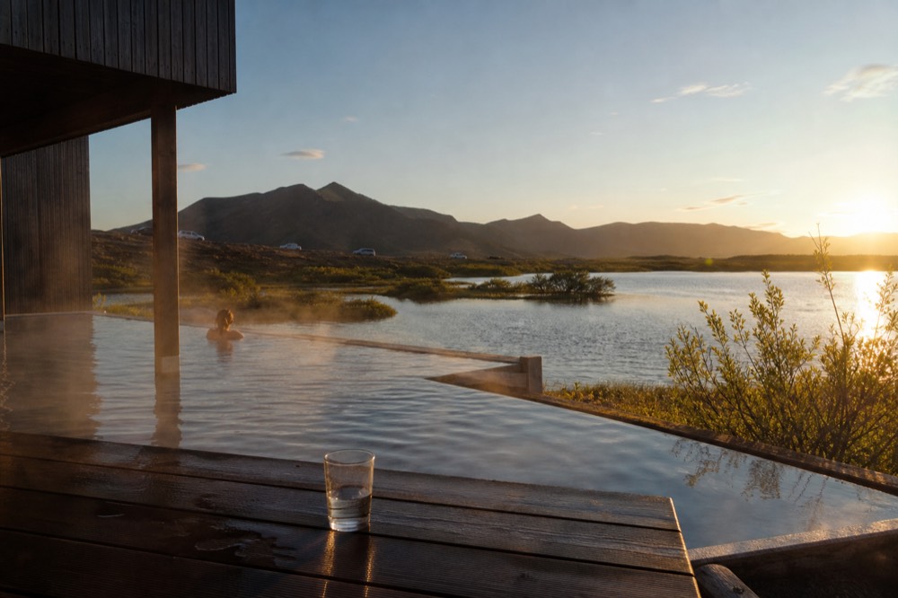 Steam drifting over warm pools at the edge of a lake in evening light
