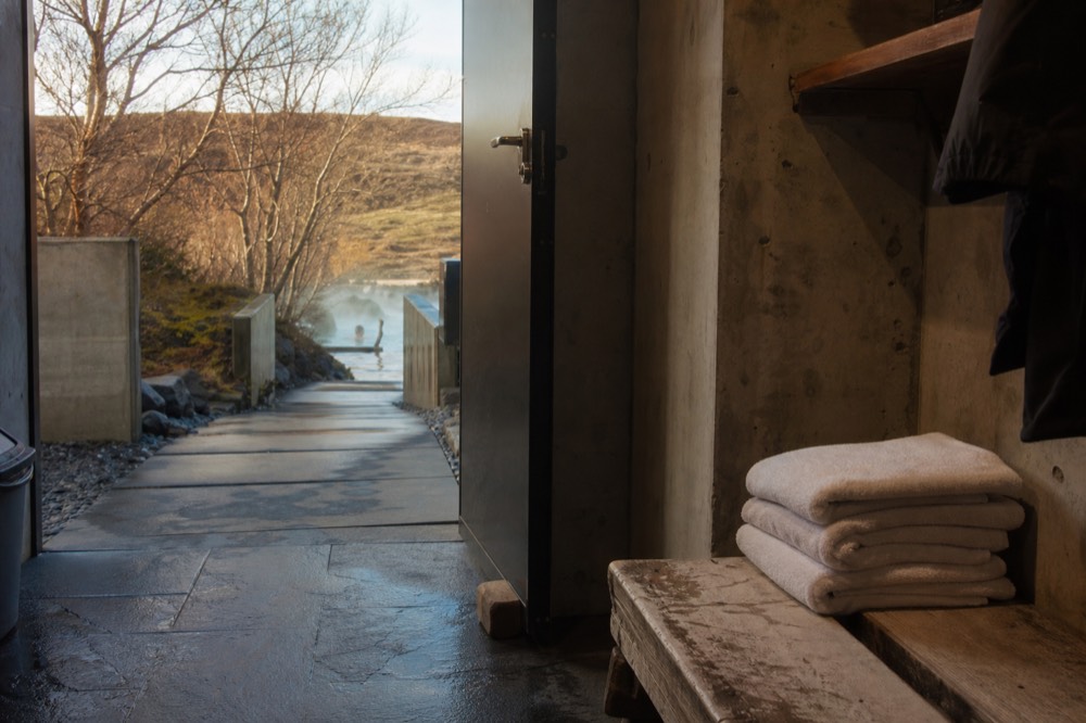 Folded white towels stacked on a wooden bench inside a spa changing room