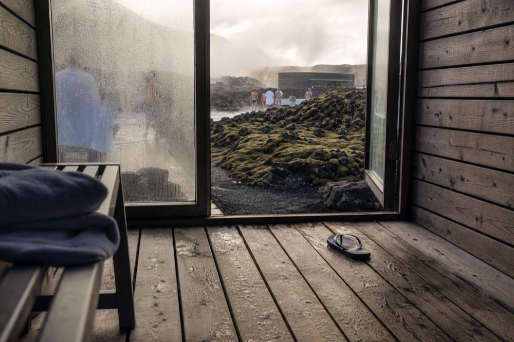 Water droplets on a wooden sauna bench beside a frosted window