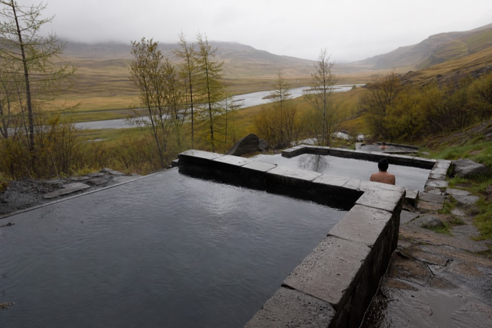 A modern geothermal lagoon terrace with pools of different sizes beside a river valley
