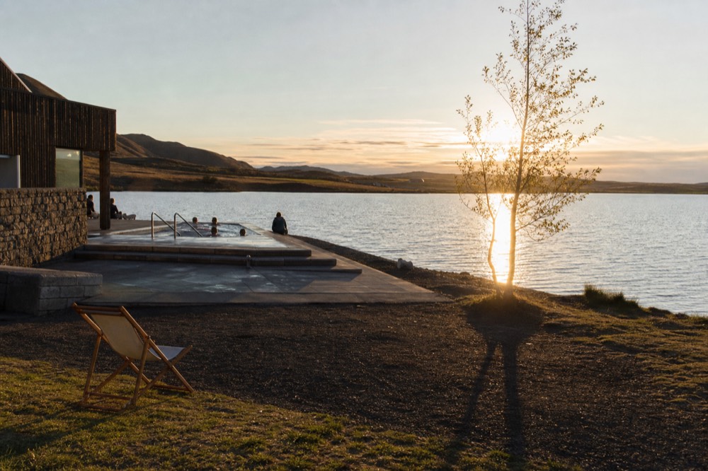 Golden evening light over a calm lake with a bathhouse terrace in the foreground
