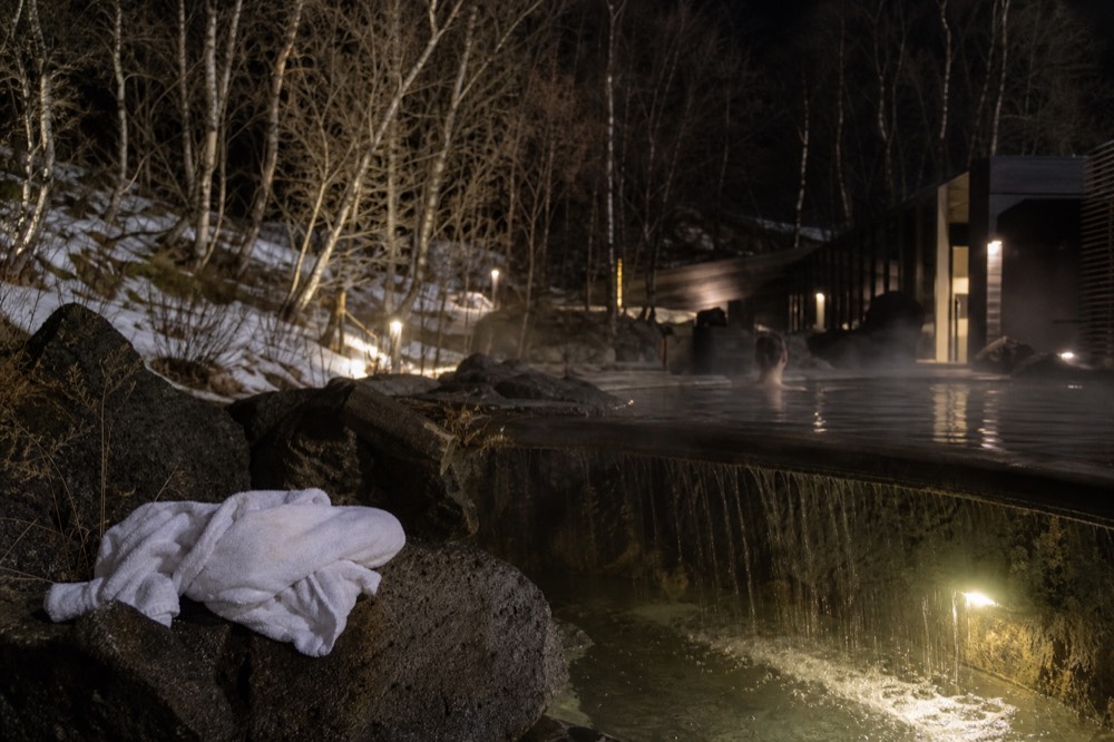 Warm water spilling over the stone edge of a geothermal pool at night