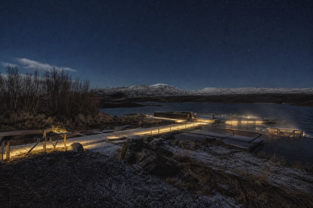 A warm outdoor pool glowing under a dark starry winter sky