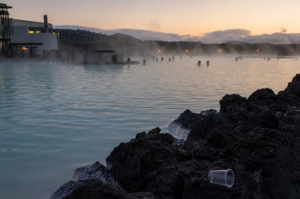 A quiet geothermal pool at dusk with steam drifting across still water