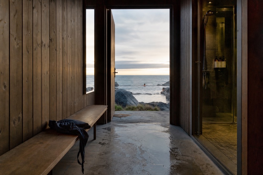 A private changing room with a wooden bench, mirror, and shower cubicle inside a lagoon facility