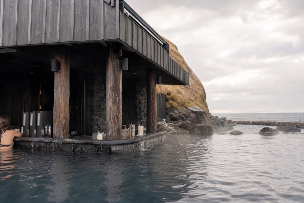 A swim-up bar counter set into the edge of a steaming geothermal lagoon