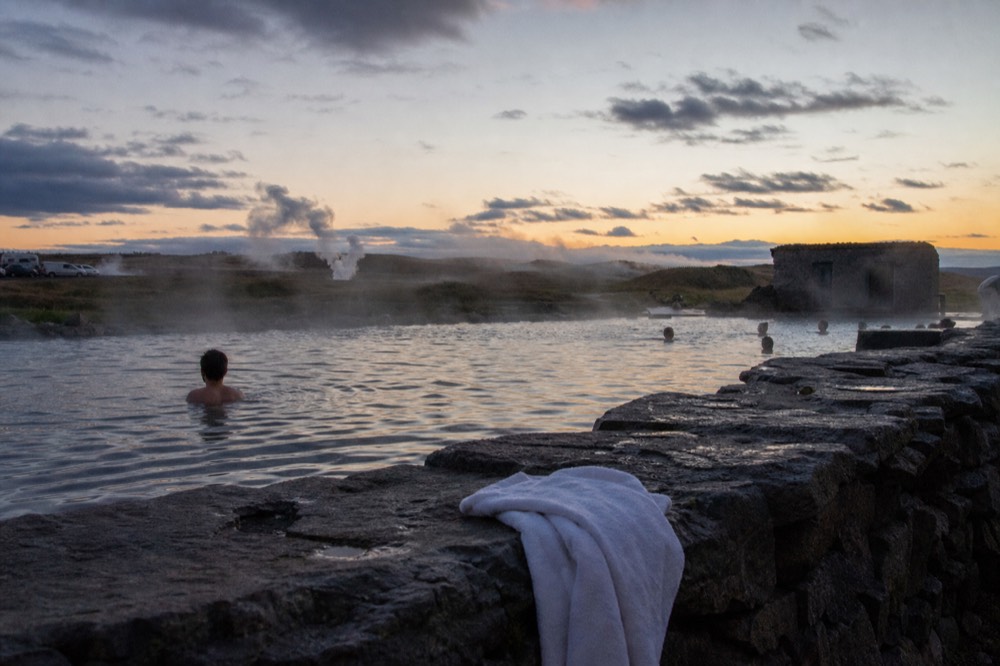 A steaming outdoor pool glowing under a darkening evening sky in Iceland