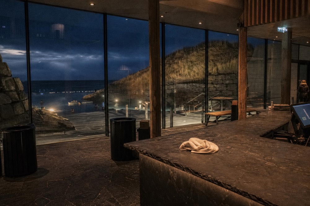 A reception desk at a geothermal bathhouse lit warmly against a dark evening