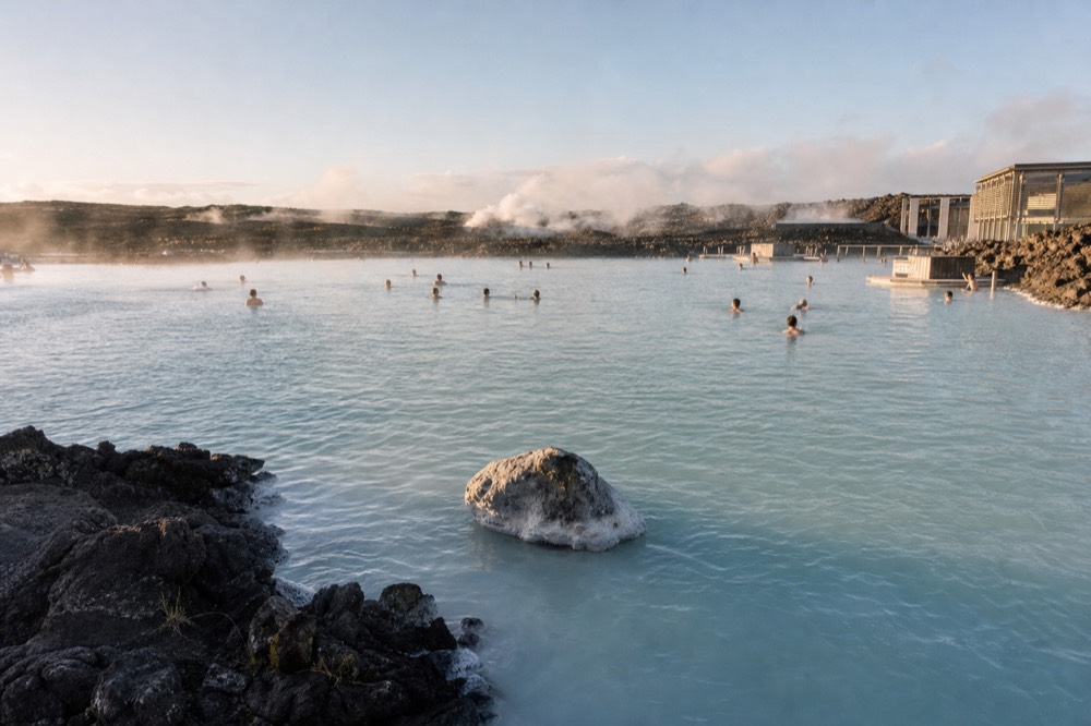 Milky blue geothermal water edged by black lava fields with a low horizon line