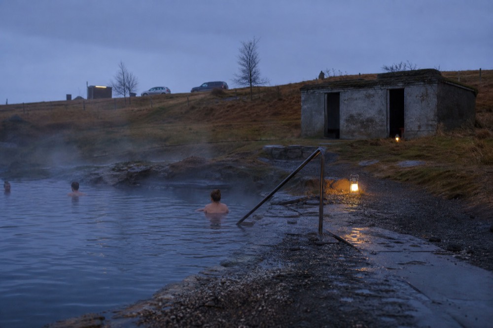 A quiet geothermal pool at dusk with steam and a low horizon