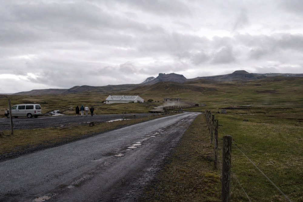 A rural road through flat farmland toward distant mountains in south Iceland