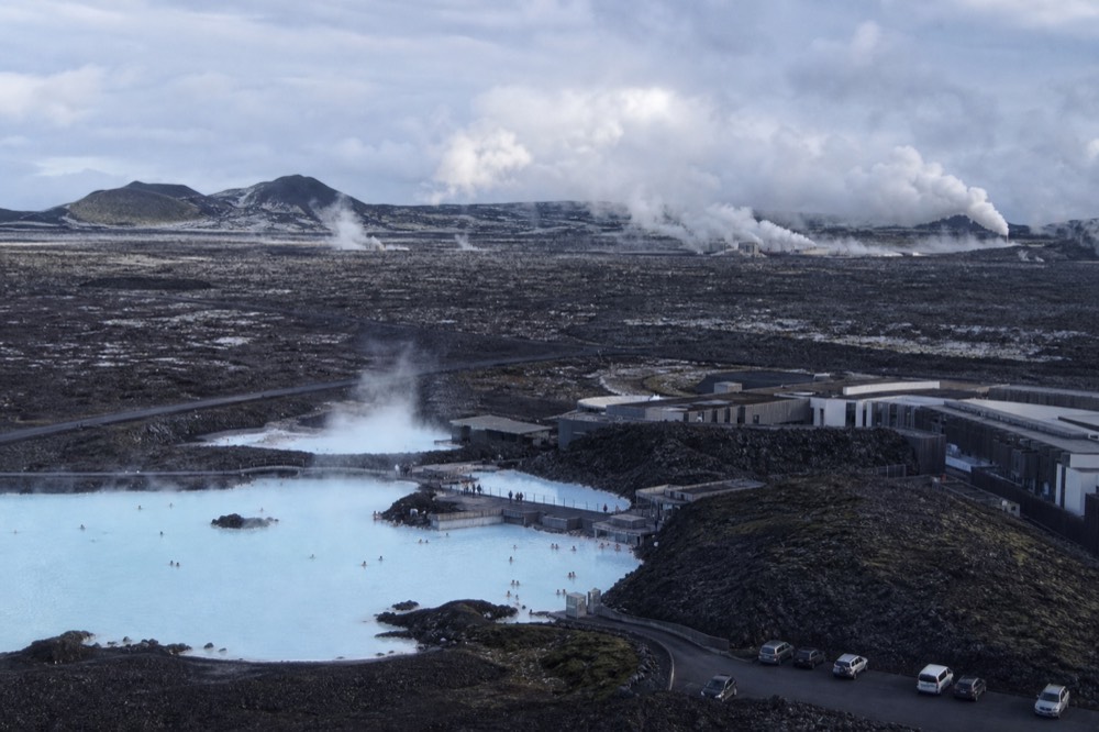 Two lagoons steaming on a dark volcanic coastline at different times of day