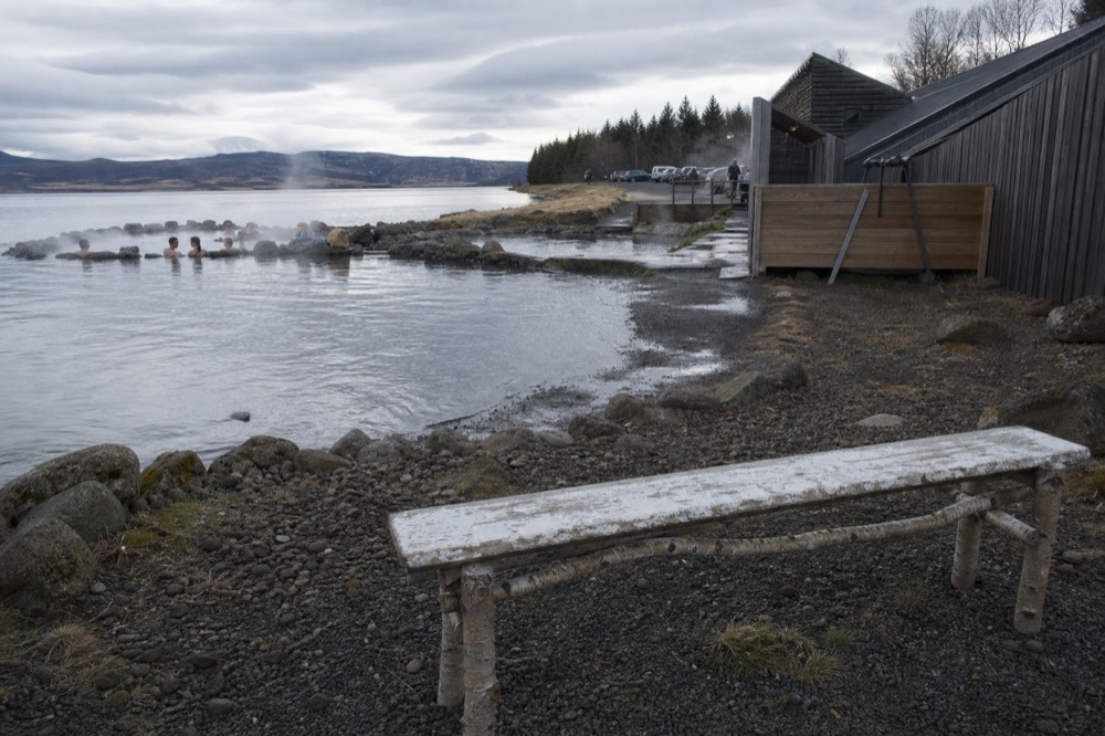 Steam rising from pools beside a calm lake shoreline