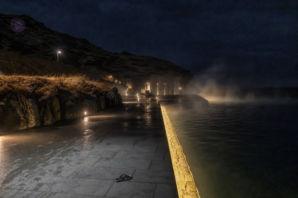 Illuminated lagoon edge after dark with steam drifting