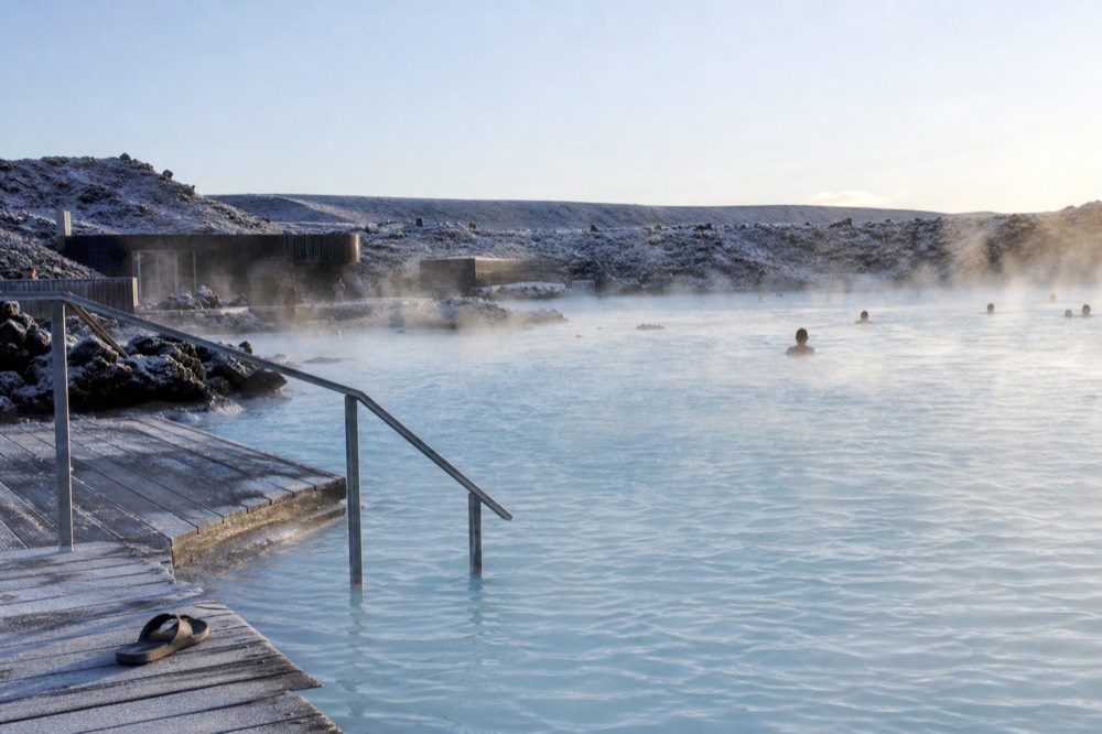 A wide geothermal lagoon steaming beside a volcanic landscape